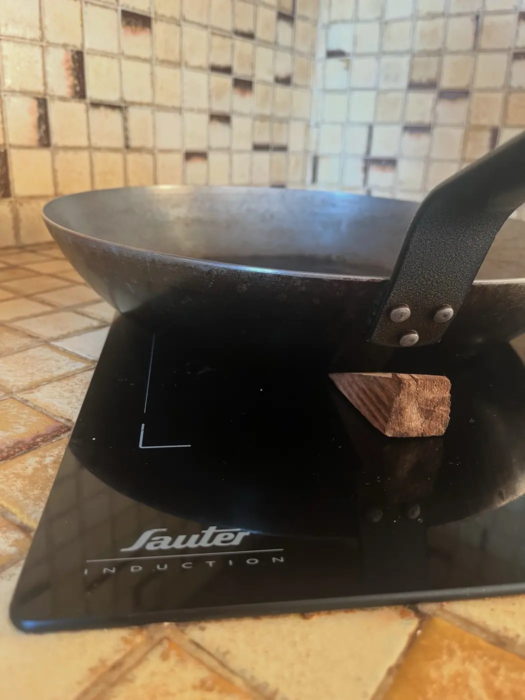 Grande poêle De Buyer de 36 cm devenue instable sur induction et maintenue avec une petite cale en bois
